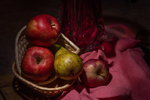 Apples and pear in a wicker basket on a wooden table.