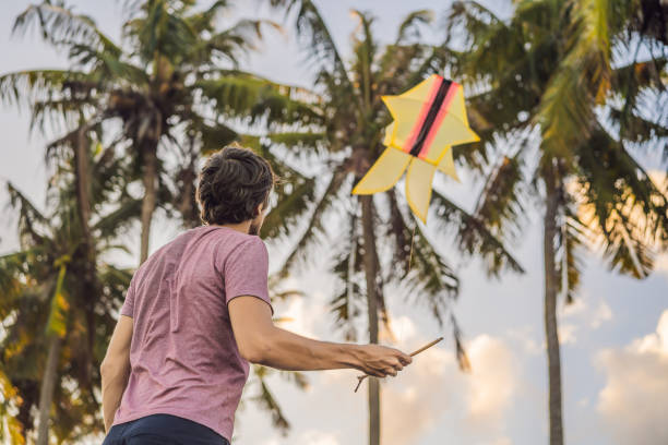 young men flying a kite at sunset on the beach