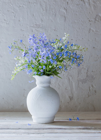 spring flowers in vase on background white old wall