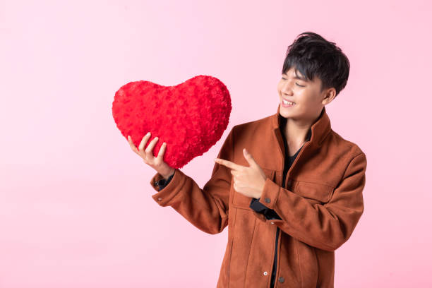 발렌타인 데이 콘셉트, 분홍색 빈 복사 공간 스튜디오 배경에 고립 된 사랑에 빨간 하트 모양의 베개를 들고 아시아 남자 잘 생긴 젊은. - heart shape business valentines day businessman 뉴스 사진 이미지