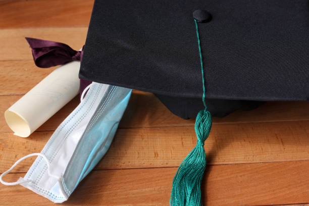 istock Graduation hat and diploma certificate on a wooden background together with protective medical mask 1314293831