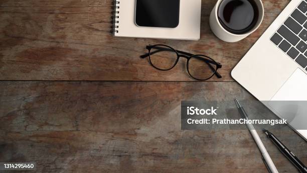 Above View Of Computer Laptop Coffee Cup Smart Phone Eye Glasses And Notebook On Wooden Table Stock Photo - Download Image Now