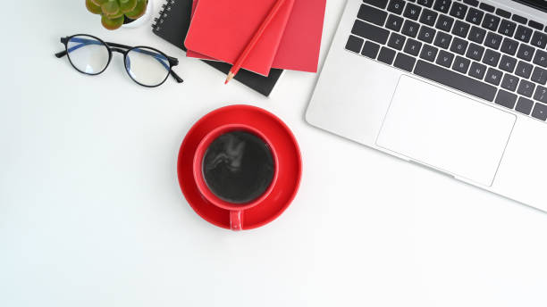 istock Above view of modern workspace with laptop computer, coffee cup, notebook and glasses on white table. 1314295483