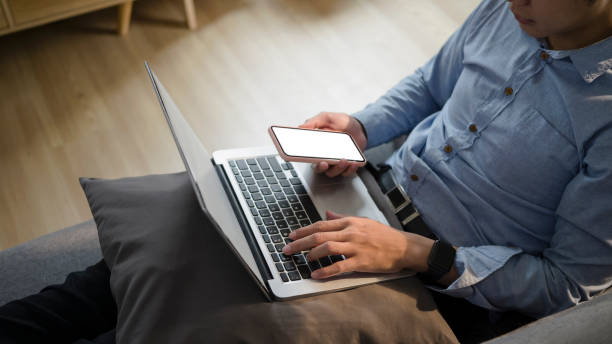 istock Cropped sot of casual young man resting on sofa using laptop computer and smart phone. 1314295937