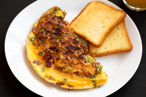 istock Homemade Denver Omelette on a white plate on a black background, side view. 1314296039