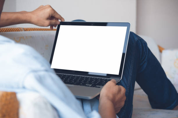 Mockup laptop computer Mockup image of casual man leaning on sofa, relax using blank screen laptop computer at home or hotel room, over shoulder view, close up looking over shoulder stock pictures, royalty-free photos & images