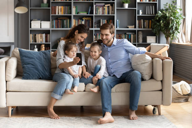 istock Happy parents relax at home using smartphone with small children 1314299048