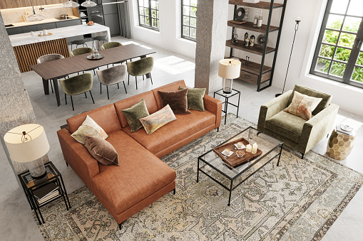 Modern apartment open plan living room interior. Large leather sofa, velvet armchair, coffee table, pillows, lamp, carpet, concrete pillars, window and dining room in the background. Copy space template. Render.