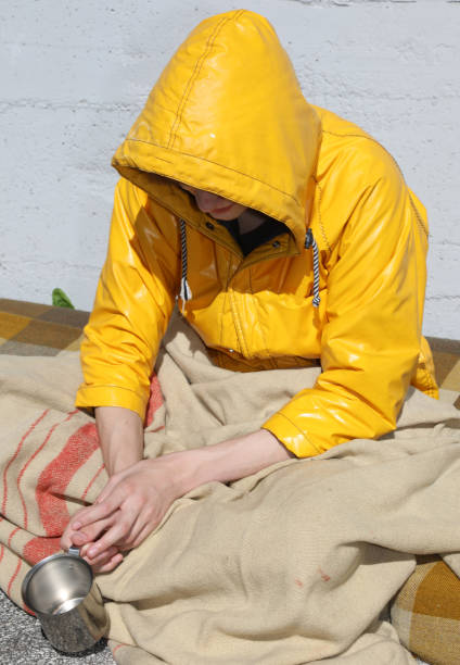 istock poor homeless young man with yellow hood on his head while begging for alms 1314301495