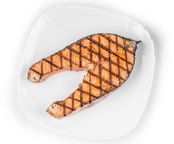 Crispy grilled salmon steak on a plate. Isolated over white background. Close-up.