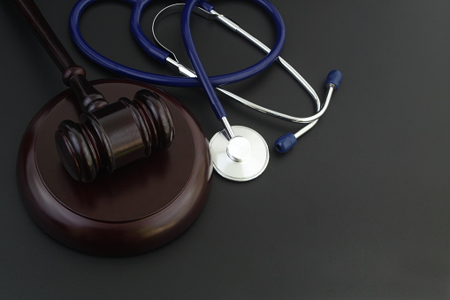 Wooden judge gavel and stethoscope with space for text. Malpractice and law in medicine concept.