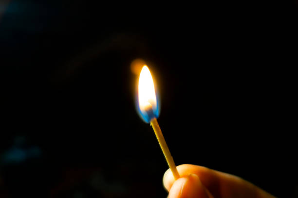 istock Burning match in hand on wooden table black background 1314311330