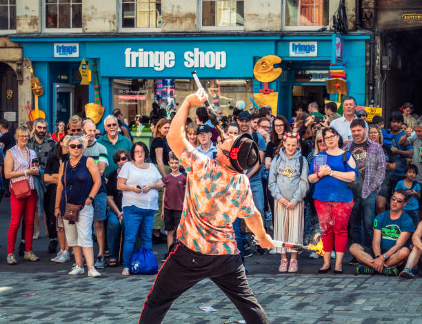Fire eating street performer during Edinburgh Festival Edinburgh, Scotland - A crowd of spectators watching a street performer on the Royal Mile in Edinburgh's Old Town, during the city's Festival Fringe, held during August. royal mile stock pictures, royalty-free photos & images