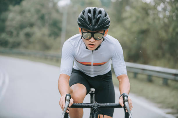 deportista ciclista profesional chino asiático corriendo en bicicleta bajo la lluvia en zona rural - cycling helmet cycling sports helmet isolated fotografías e imágenes de stock