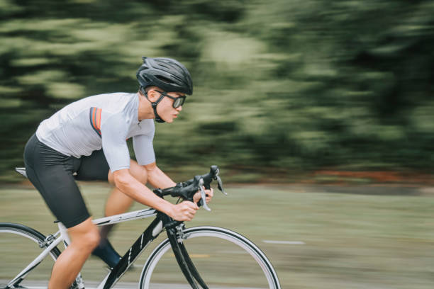 side view Asian Chinese professional cyclist athlete sportsman sprinting cycling in the rain in rural area side view Asian Chinese professional cyclist athlete sportsman sprinting cycling in the rain in rural area forward athlete stock pictures, royalty-free photos & images