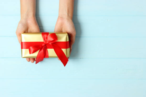 istock gift in female hands on a colored background top view. 1314326506