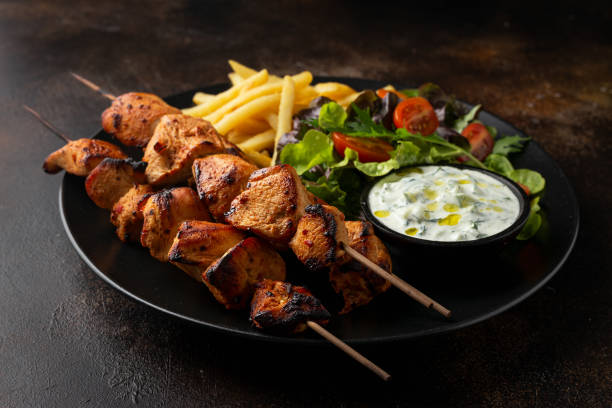 chicken fillet souvlaki, kebabs on skewers with potato chips, salad and fresh home made tzatziki - souvlaki imagens e fotografias de stock