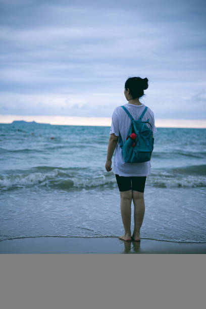 istock Woman standing on beach looking the sea 1314330065