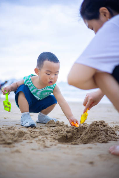istock Mother and son playing sand on the beach 1314330119