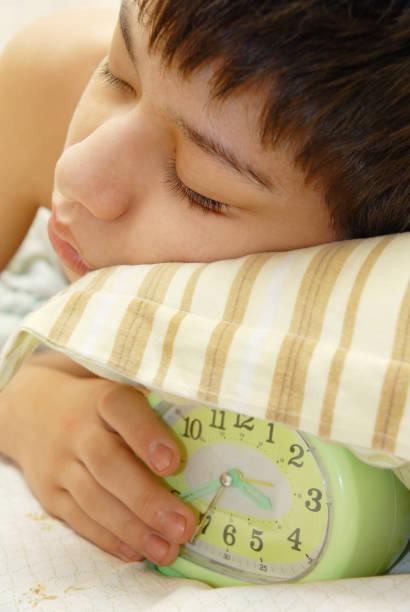 istock Deep sleep of the boy with green alarm-clock under his pillow 1314332371