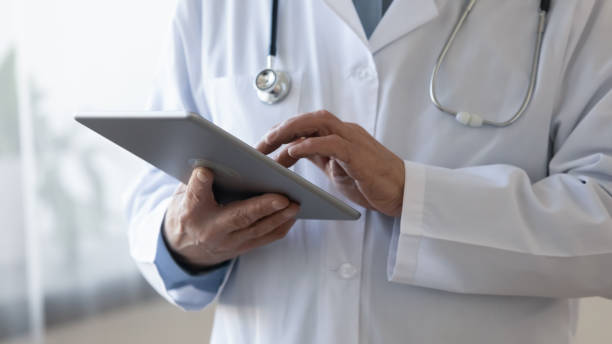 istock Close up old male doctor holding digital computer tablet. 1314334405