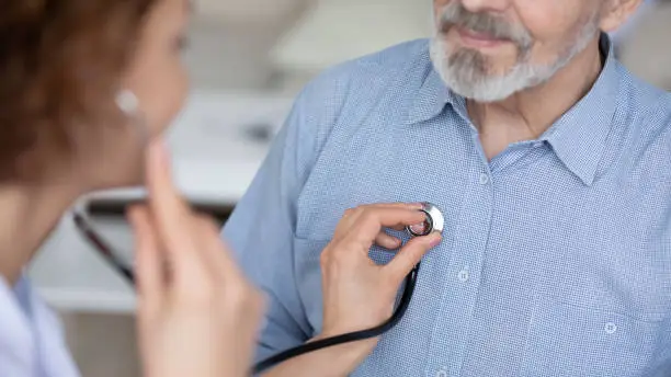 Photo of Close up young female general practitioner using stethoscope.