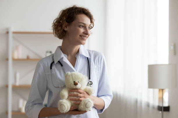 istock Smiling young kind female pediatrician holding teddy bear in hands. 1314334570