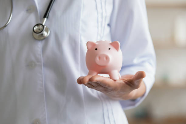 istock Young female general practitioner holding piggy bank in hands. 1314334574
