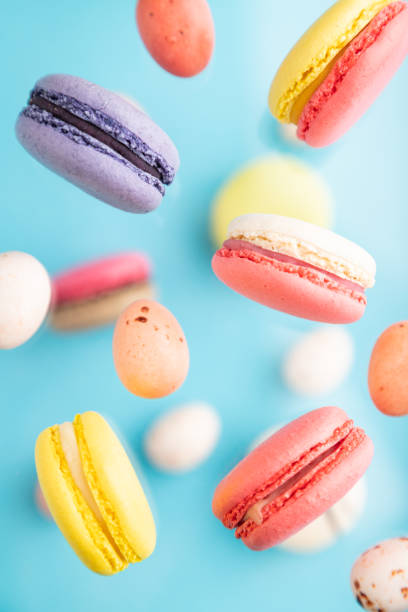 istock Multicolored flying macaroons and chocolate eggs frozen in the air on blurred blue background. top view, flat lay, close up. Breakfast, morning, concept. 1314334613