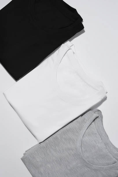 istock Three folded monochrome t shirts gray, black and white isolated over gray background 1314335819