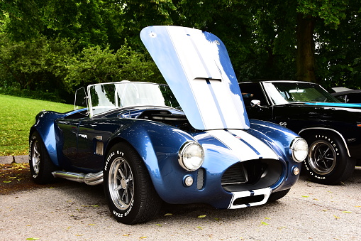 Mount Pleasant, Wisconsin / USA - July 21, 2019: A beautiful bright blue and white 427 powered Shelby Cobra with hood raised at local car show on display.