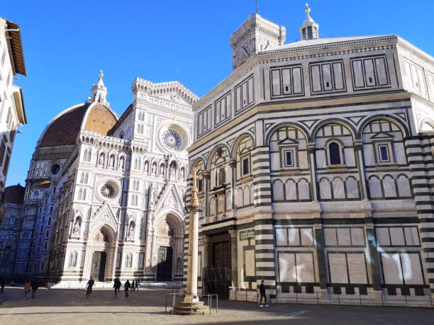 The majestic Santa Maria Del Fiore Cathedral and the Battistero in Duomo square, Florence, Italy. People walking on the famous square.