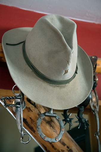 Old western hat handing on red wall over old spurs hanging under it, in Montana, western USA.