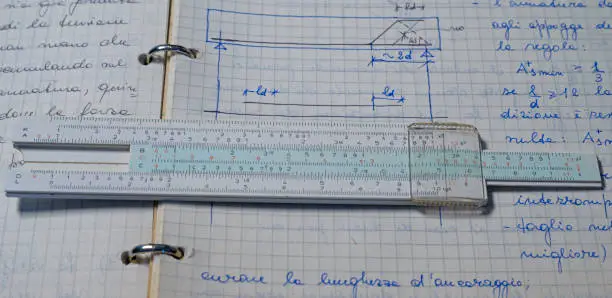 Pencil, old slide rule and scientific electronic calculator page with the calculations in progress