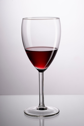 Two wine glasses in toasting gesture with big splashing. Alcohol concept. Two glasses of wine on the gray background. Two transparent glasses. Trendy color. Merging alcohol