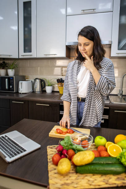 istock woman cooking checking recipe at laptop 1314356747