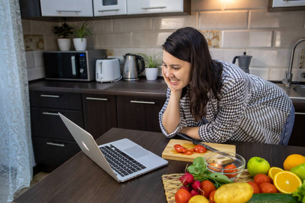 istock woman cooking checking recipe at laptop 1314356782