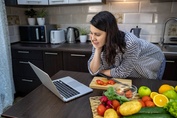 istock woman cooking checking recipe at laptop 1314356793