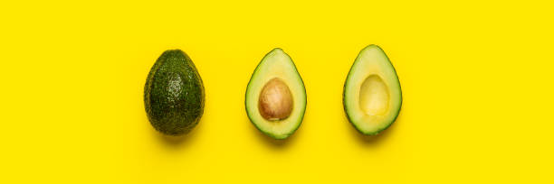 istock cut with a bone and a whole avocado on a bright yellow background. Top view, flat lay. Banner 1314356890