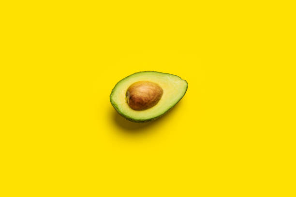 istock fresh ripe slice, half an avocado on a bright yellow background. Top view, flat lay 1314357087
