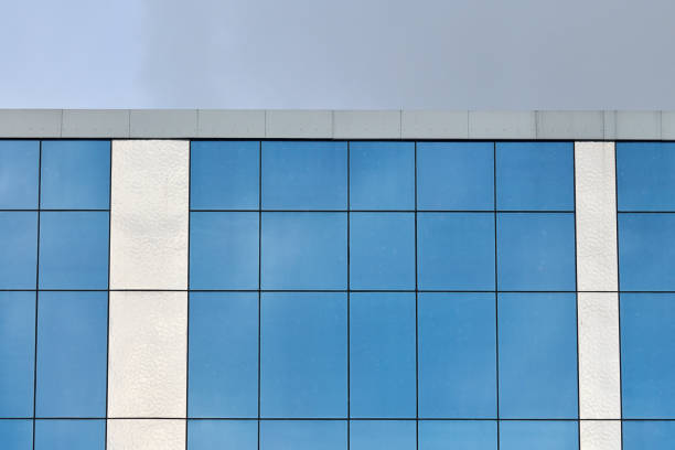 Modern glass office building with blue sky background. Bank financial office building wall. Real estate.