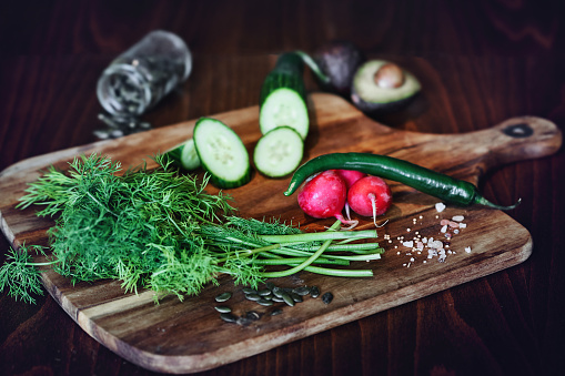 Wooden board of chopped dill with a knife on a light gray background. Cooking homemade food