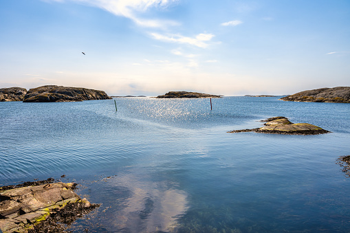 A picture of a beautiful rock island. Ocean and blue sky with thin clouds in the background. Picture from the the Weather Islands, on the Swedish West coast