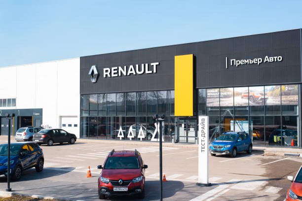 Car dealership of French automobile corporation Renault, outside. Building facade, parking and signboard with logo on clear blue sky background. Smolensk, Russia 04.18.2021 stock photo