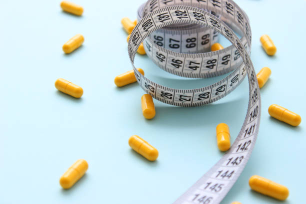 istock Measuring tape and diet pills on a colored background close-up. 1314362173