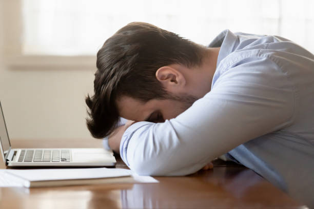 istock Tired young man fall asleep on table working on laptop 1314362432