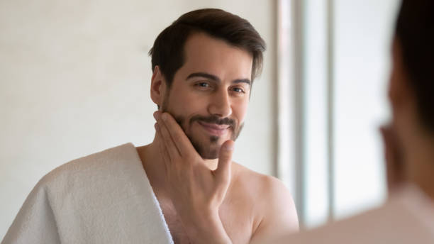 istock Smiling young Caucasian man look in mirror in bathroom 1314362477