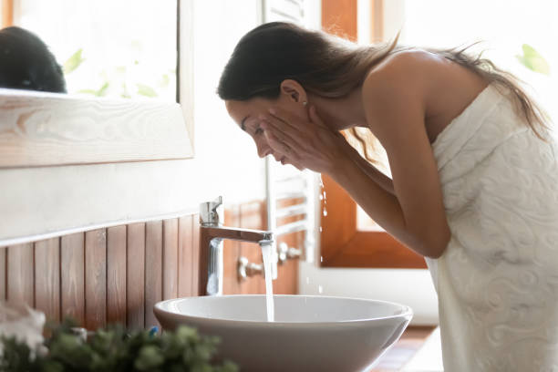 istock Young woman wash face under running water 1314362502