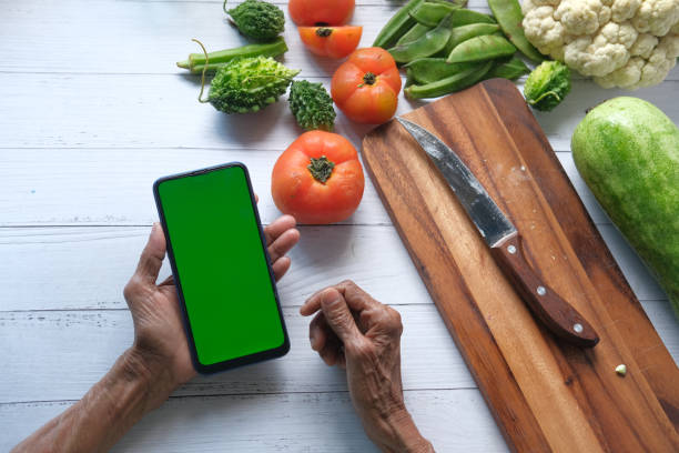 senior women hand using smart phone and fresh vegetables on table