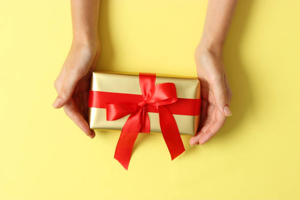 istock gift in female hands on a colored background top view. 1314363974